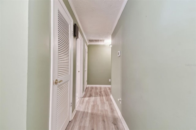 hall featuring light wood-type flooring and a textured ceiling