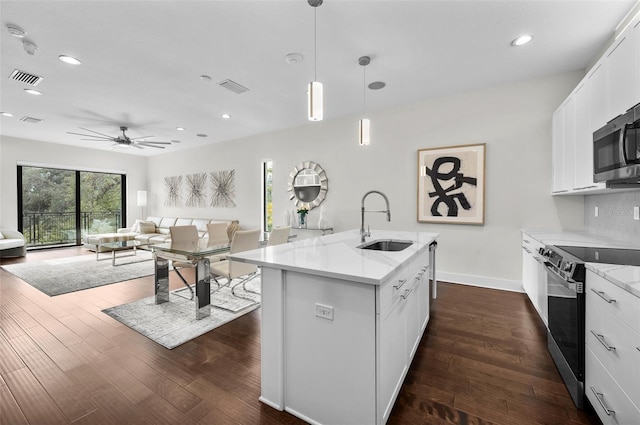 kitchen featuring appliances with stainless steel finishes, white cabinetry, hanging light fixtures, sink, and an island with sink