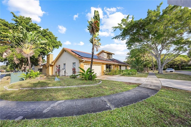 view of front facade with a garage, a front yard, and solar panels