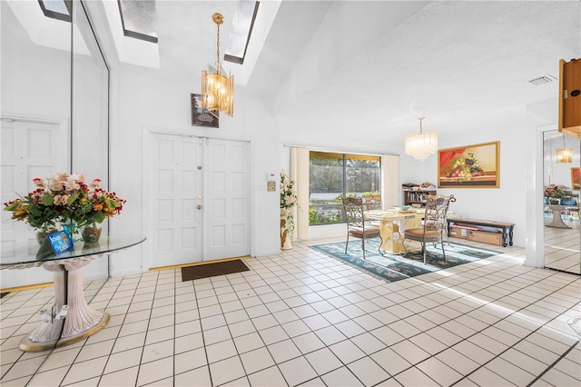 tiled foyer entrance with a chandelier, a textured ceiling, and high vaulted ceiling