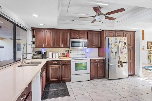 kitchen with stainless steel appliances, sink, a raised ceiling, ceiling fan, and light tile patterned floors