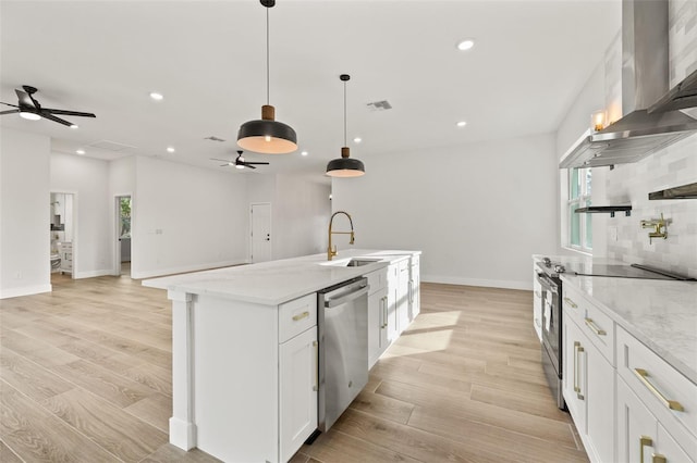 kitchen featuring appliances with stainless steel finishes, white cabinetry, sink, ventilation hood, and decorative light fixtures