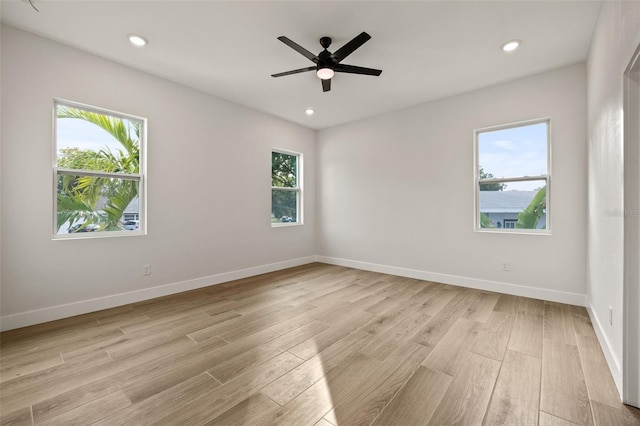 spare room with light wood-type flooring, ceiling fan, and a wealth of natural light