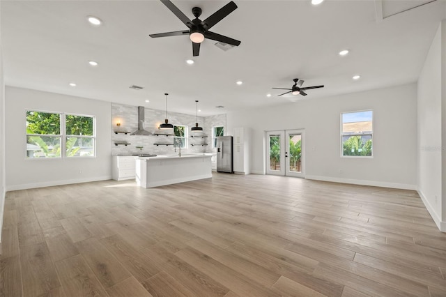 unfurnished living room with ceiling fan, light hardwood / wood-style flooring, and french doors