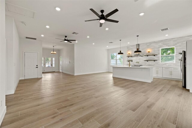 unfurnished living room with ceiling fan, plenty of natural light, and light hardwood / wood-style flooring