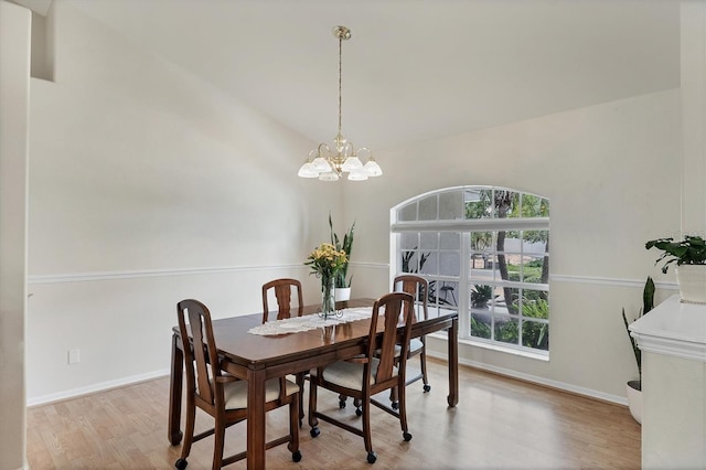 dining space with lofted ceiling, a chandelier, and light hardwood / wood-style flooring