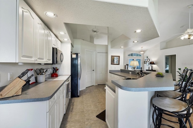 kitchen with a breakfast bar, sink, white cabinets, electric range, and ceiling fan