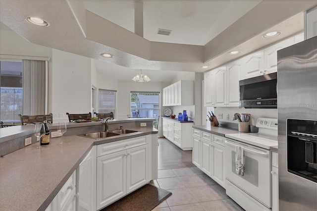 kitchen featuring sink, white cabinets, light tile patterned floors, stainless steel appliances, and a textured ceiling