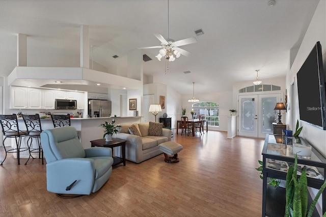 living room featuring ceiling fan, high vaulted ceiling, light wood-type flooring, and french doors