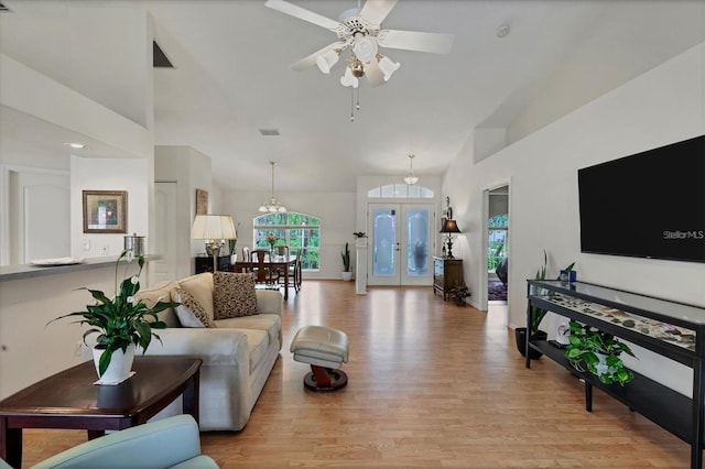 living room with a high ceiling, french doors, ceiling fan, and light wood-type flooring