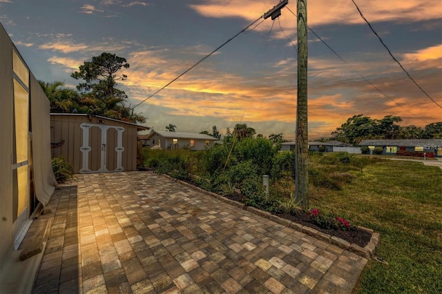 patio terrace at dusk featuring a shed and a yard