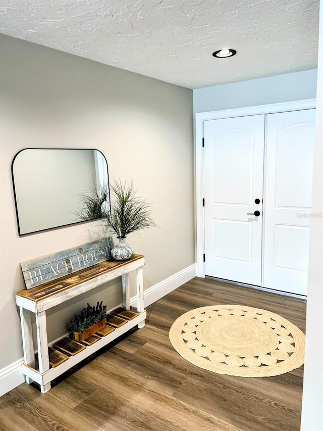 foyer entrance with dark wood-type flooring and a textured ceiling