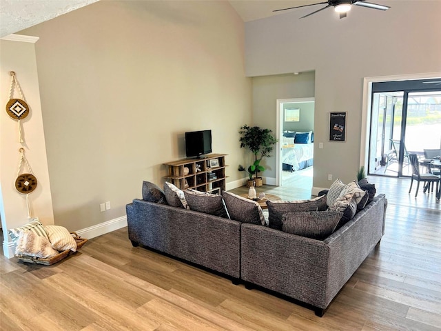 living room featuring ceiling fan, a high ceiling, and hardwood / wood-style floors