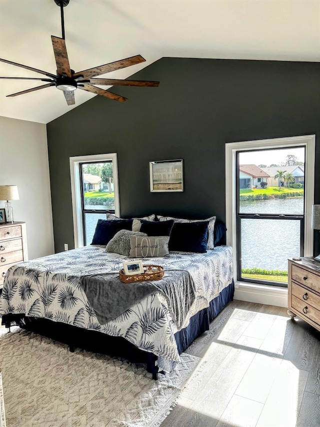 bedroom with hardwood / wood-style floors, a water view, vaulted ceiling, and ceiling fan