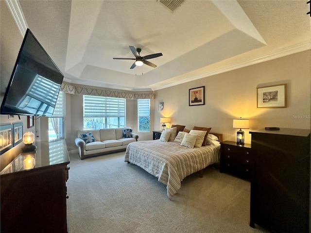 bedroom featuring a textured ceiling, ornamental molding, carpet flooring, ceiling fan, and a tray ceiling