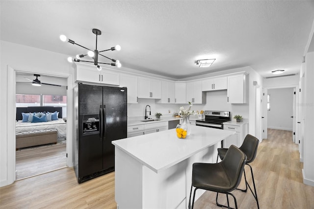 kitchen with sink, decorative light fixtures, white cabinets, stainless steel electric stove, and black fridge with ice dispenser