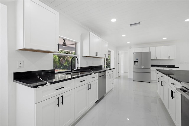 kitchen featuring sink, stainless steel appliances, white cabinetry, and dark stone countertops