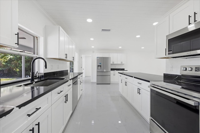 kitchen with white cabinets, appliances with stainless steel finishes, ornamental molding, and sink