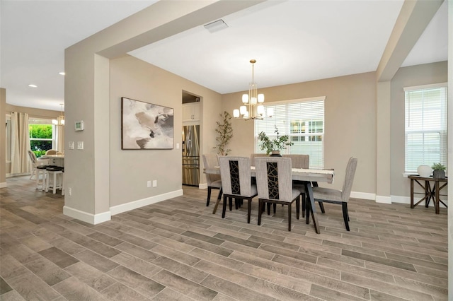 dining room featuring wood-type flooring, an inviting chandelier, and plenty of natural light