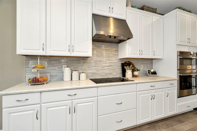 kitchen with black electric stovetop, decorative backsplash, stainless steel double oven, and white cabinetry