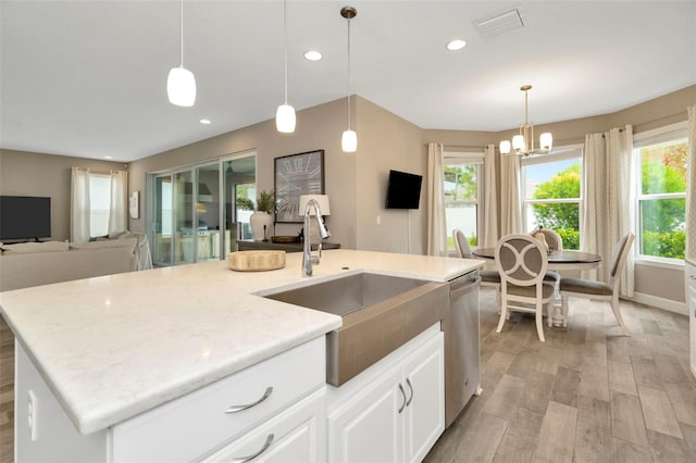 kitchen with dishwasher, decorative light fixtures, white cabinetry, an island with sink, and sink