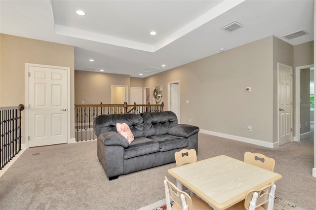 carpeted living room with a tray ceiling