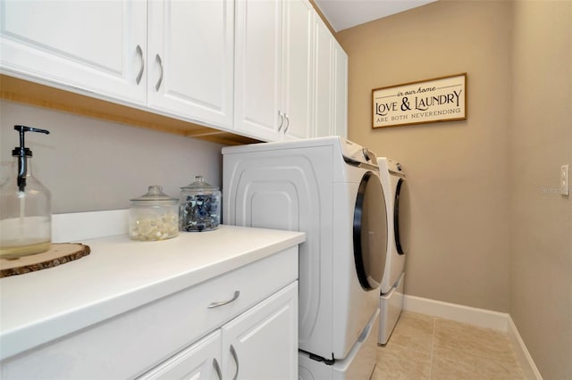 clothes washing area featuring cabinets, light tile patterned floors, and washing machine and dryer