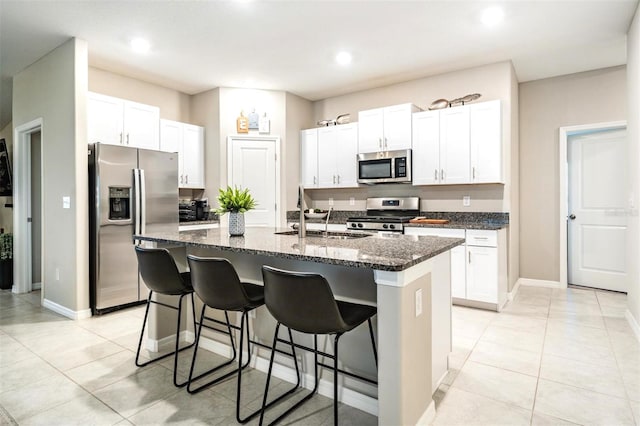 kitchen with white cabinetry, appliances with stainless steel finishes, a kitchen island with sink, and sink