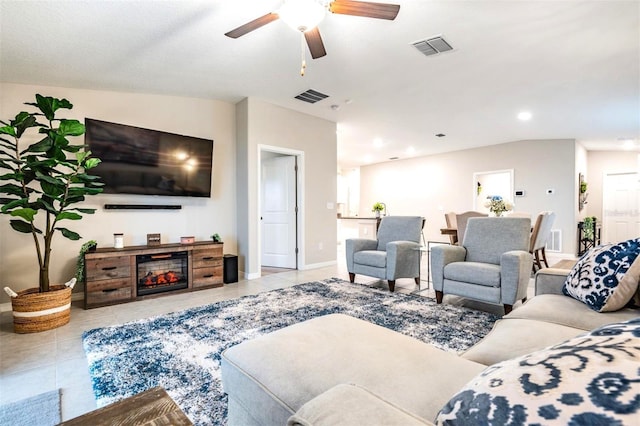 tiled living room with ceiling fan, lofted ceiling, and a fireplace