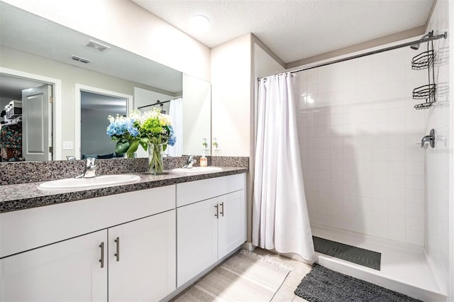 bathroom with tile patterned floors, curtained shower, a textured ceiling, and vanity