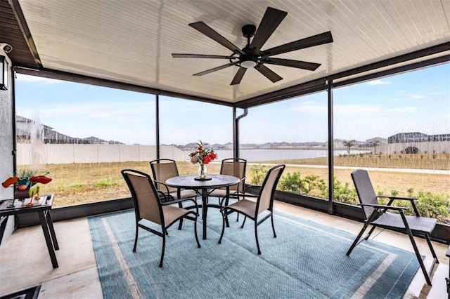 sunroom / solarium with a water view, ceiling fan, and a healthy amount of sunlight