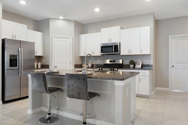 9805 Lemon Drop Loop, Sun City Center, FL 33573 - kitchen featuring stainless steel appliances, light tile patterned flooring, white cabinets, a center island with sink, and recessed lighting
