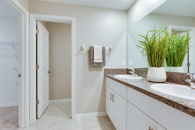 9805 Lemon Drop Loop, Sun City Center, FL 33573 - bathroom featuring double vanity, a spacious closet, and baseboards