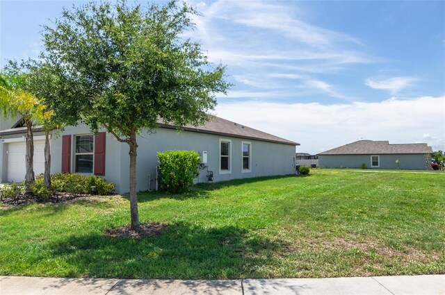 9805 Lemon Drop Loop, Sun City Center, FL 33573 - view of side of property featuring a lawn, stucco siding, and an attached garage