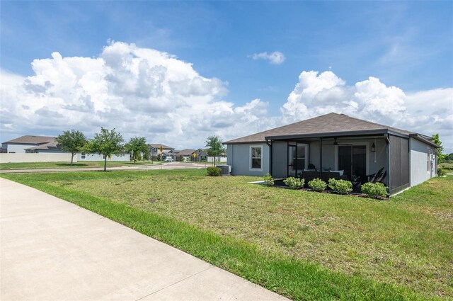 9805 Lemon Drop Loop, Sun City Center, FL 33573 - view of side of home featuring a sunroom, a lawn, central AC unit, and roof with shingles