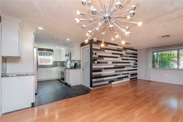 unfurnished living room with sink, hardwood / wood-style flooring, and a notable chandelier