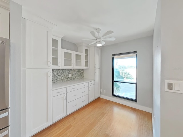 kitchen with refrigerator, white cabinets, backsplash, ceiling fan, and light hardwood / wood-style floors