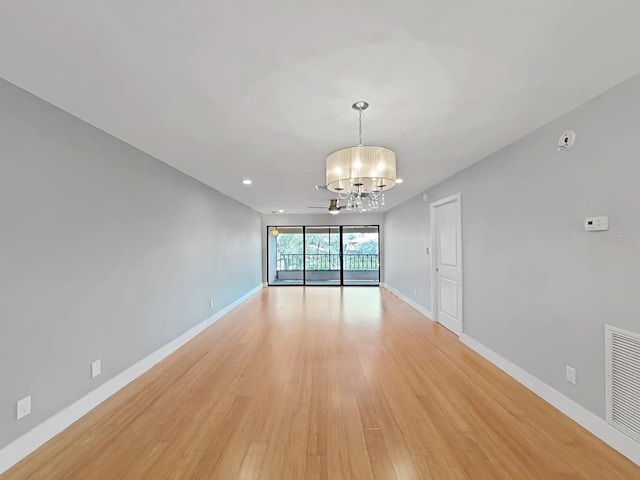 unfurnished room featuring a chandelier and light hardwood / wood-style floors