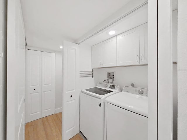 laundry area with cabinets, washing machine and clothes dryer, and light hardwood / wood-style flooring