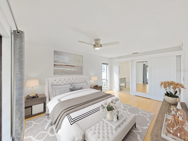 bedroom with connected bathroom, light hardwood / wood-style flooring, and ceiling fan