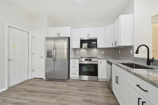 kitchen with sink, light hardwood / wood-style flooring, appliances with stainless steel finishes, white cabinetry, and light stone countertops