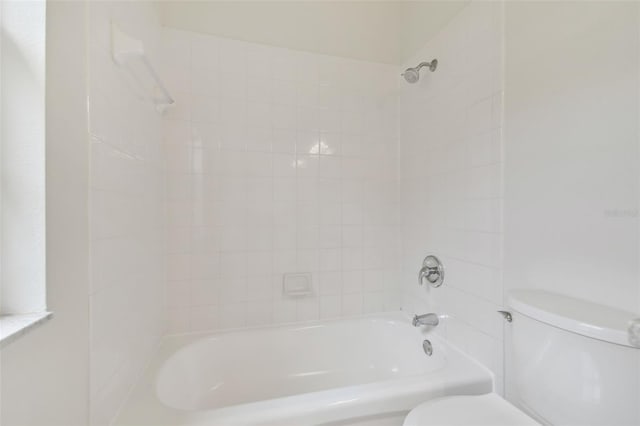 bathroom with tiled shower / bath combo and toilet