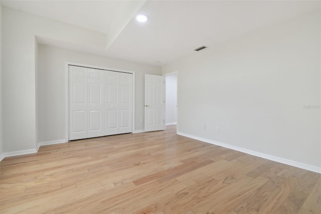 unfurnished bedroom with light wood-type flooring and a closet