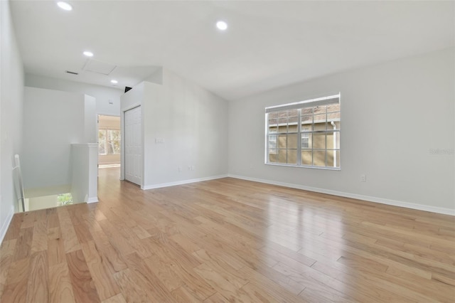 unfurnished room featuring lofted ceiling, a wealth of natural light, and light hardwood / wood-style floors