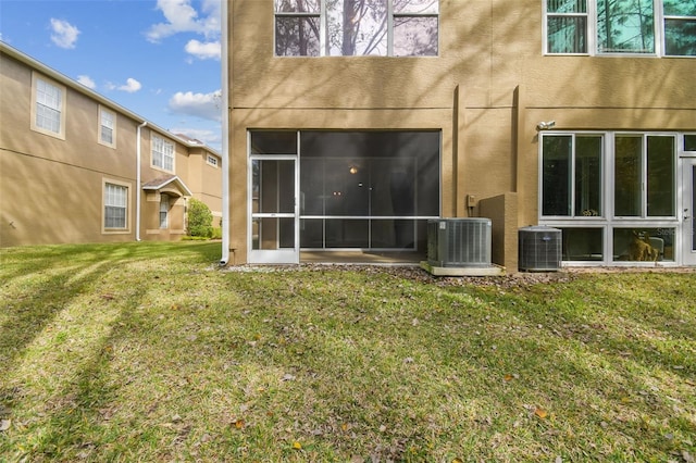 rear view of property with a sunroom, a lawn, and central air condition unit