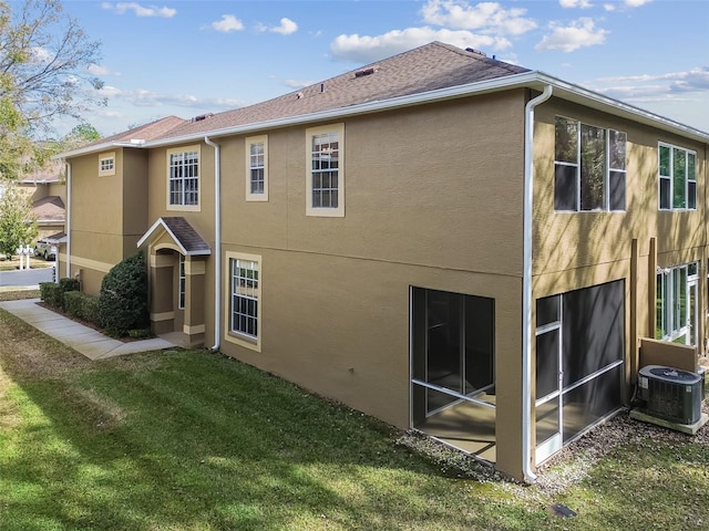 back of property featuring cooling unit, a lawn, and a sunroom