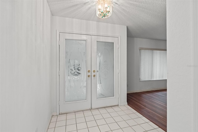 foyer entrance featuring a textured ceiling, light tile patterned floors, and french doors