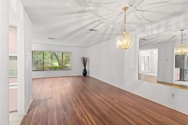 unfurnished living room featuring wood-type flooring, a textured ceiling, and a notable chandelier