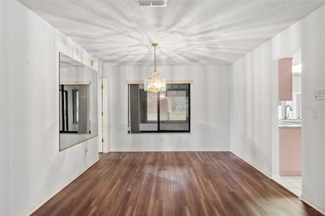 unfurnished dining area featuring dark wood-type flooring, sink, and an inviting chandelier