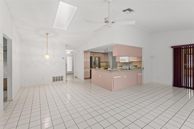 kitchen with kitchen peninsula, stainless steel fridge, ceiling fan, lofted ceiling with skylight, and light tile patterned floors